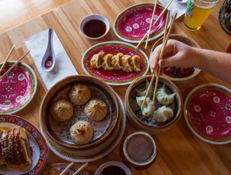 A person uses chopsticks to grab a dumpling amid a table full of delicious food at Bing Bing Dim Sum in South Philadelphia