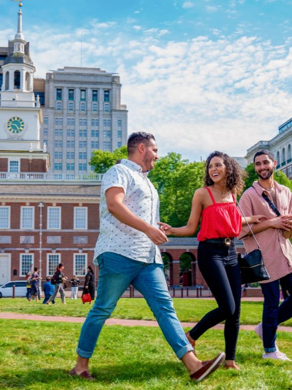 Two men and a woman walking across Independence Mall