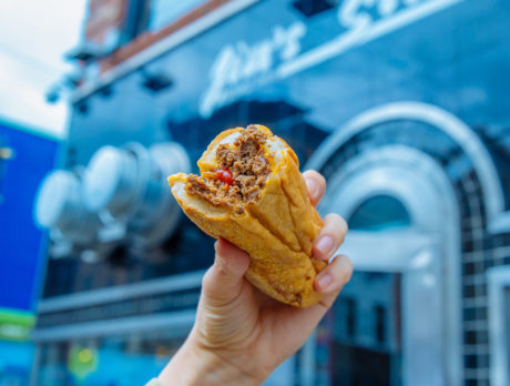 A cheesesteak hoisted triumphantly in front of Jim's Steaks in Philadelphia