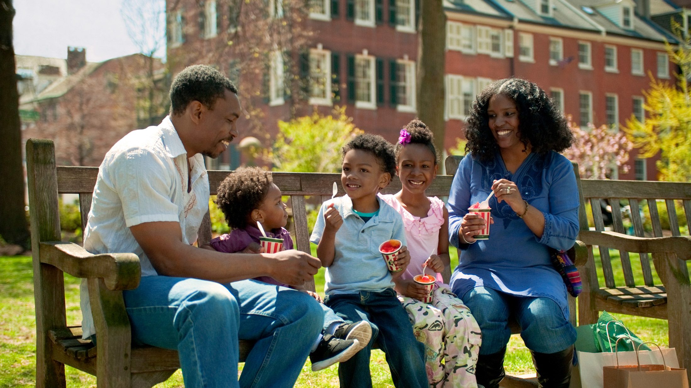 A family of five enjoys cups of water ice on a bench in Washington Square