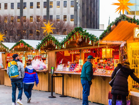 Socially distant shoppers browse the Christmas Village in Philadelphia during the day, where vendors sell gifts at wooden booths.