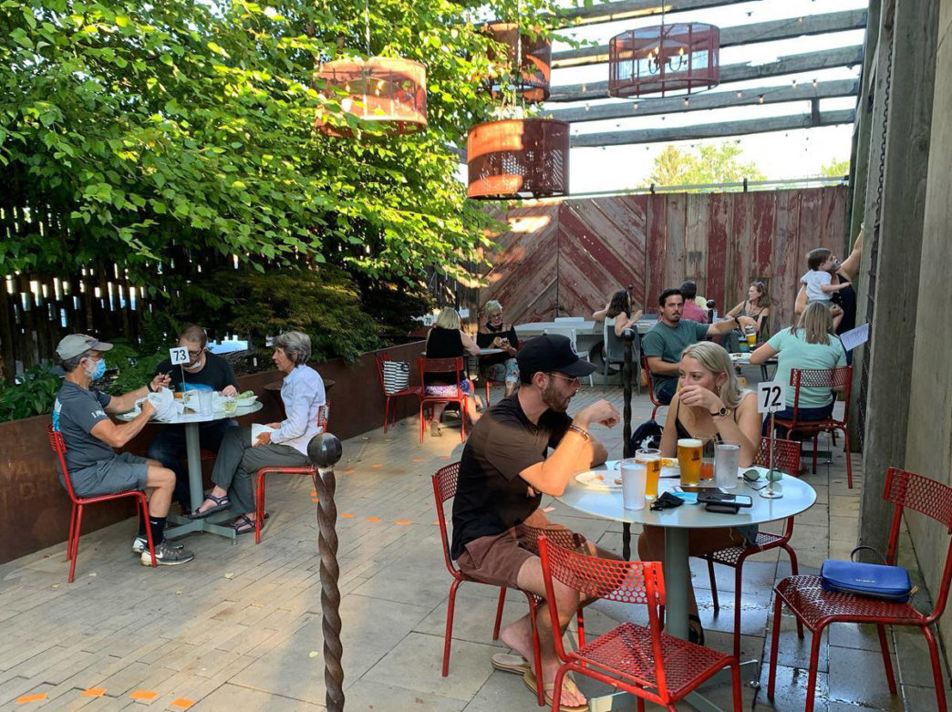 Customers eat at orange tables beneath chandeliers and hanging trees at the Market at the Fareway in Chestnut Hill, Philadelphia