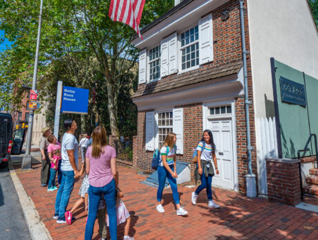 Family viewing and teenagers walking by the exterior of the Betsy Ross House.