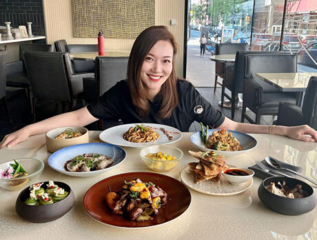 Chef Sally Song of Dim Sum Garden smiles for the camera while sitting behind a table of menu items.