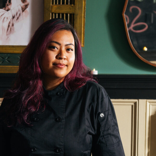 Chef Diana-Widjojo of Rice and Sambal poses for a photo in her restaurant while wearing a black chef jacket.