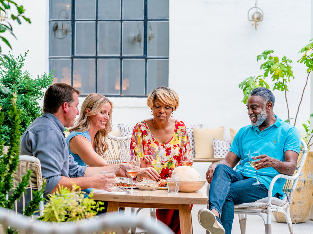 Four people sit around a patio table enjoying a meal in the outdoor dining space at Suraya in Philadelphia.