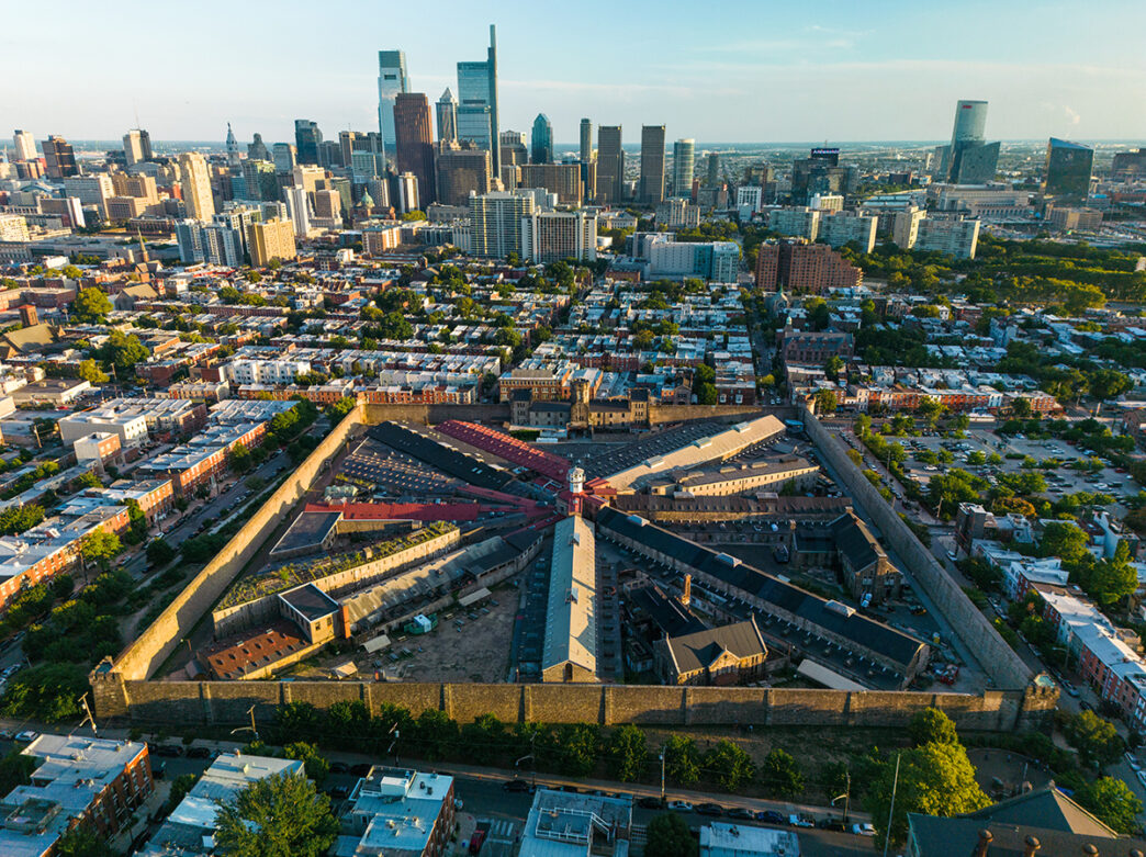 An aerial view of Eastern State Penitentiary with the Philadelphia skyline in the background.