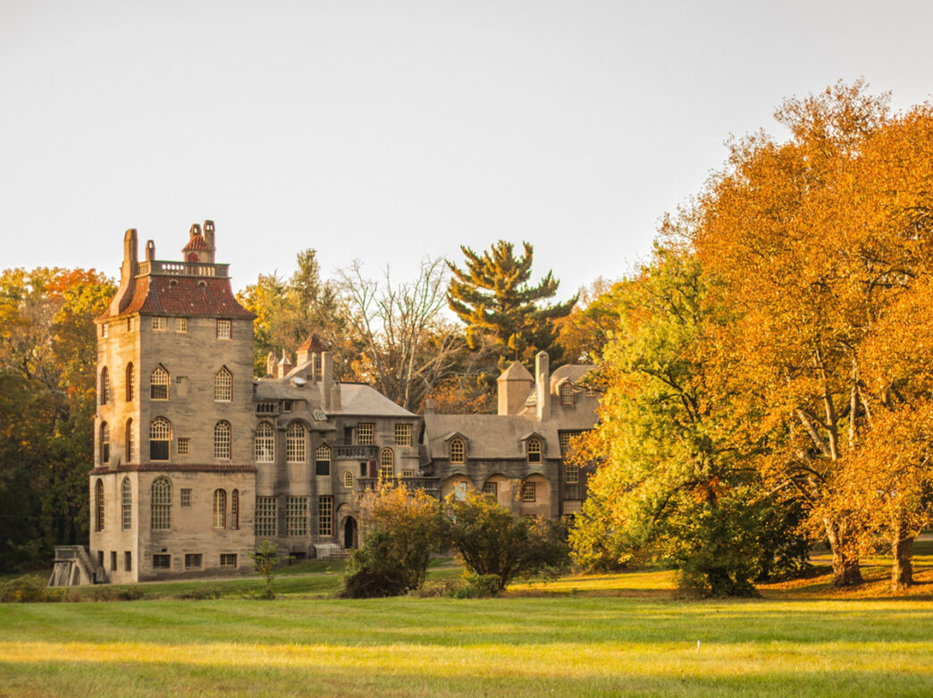 The Fonthill Castle is surrounded by trees with orange and yellow leaves during fall.
