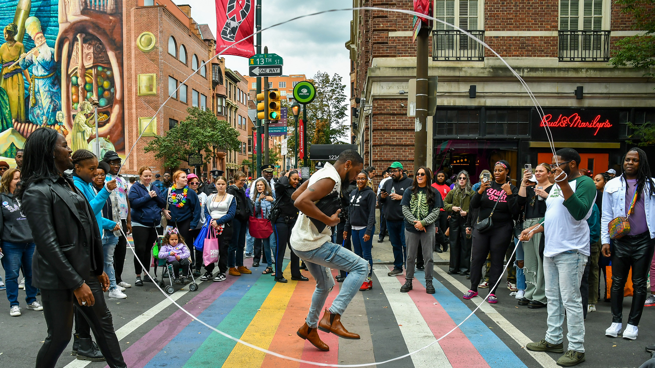 A person jumps rope above a rainbow crosswalk during OURFest in Philadelphia