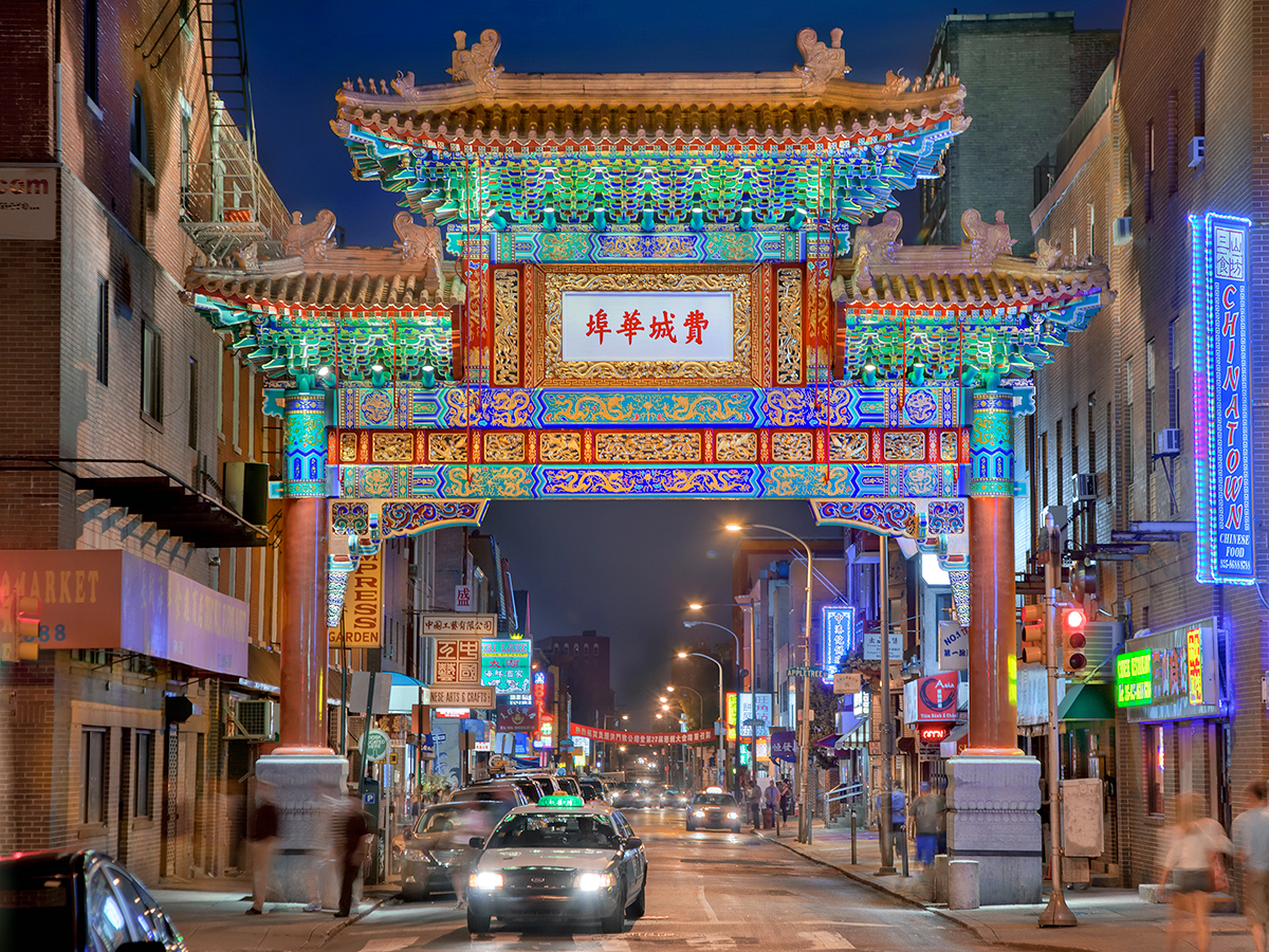The Chinatown Friendship Gate painted with bright colors is illuminated with up lighting at night.