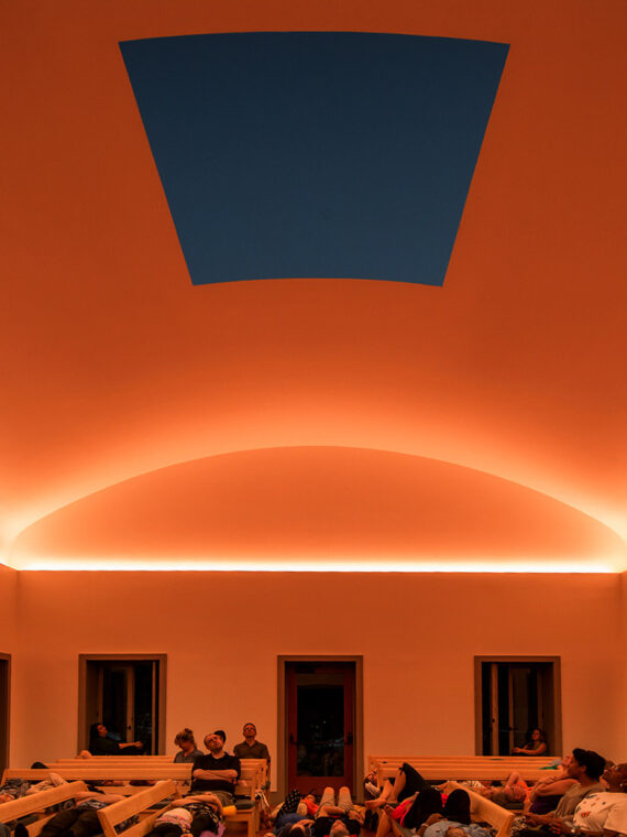 Visitors at Chestnut Hill Skyspace watch the sunset during a hole in the roof while light is projected on the ceiling around it