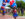 People walking in a parade line holding colorful balloons during Red, White & Blue To-Do. A woman waves at the camera