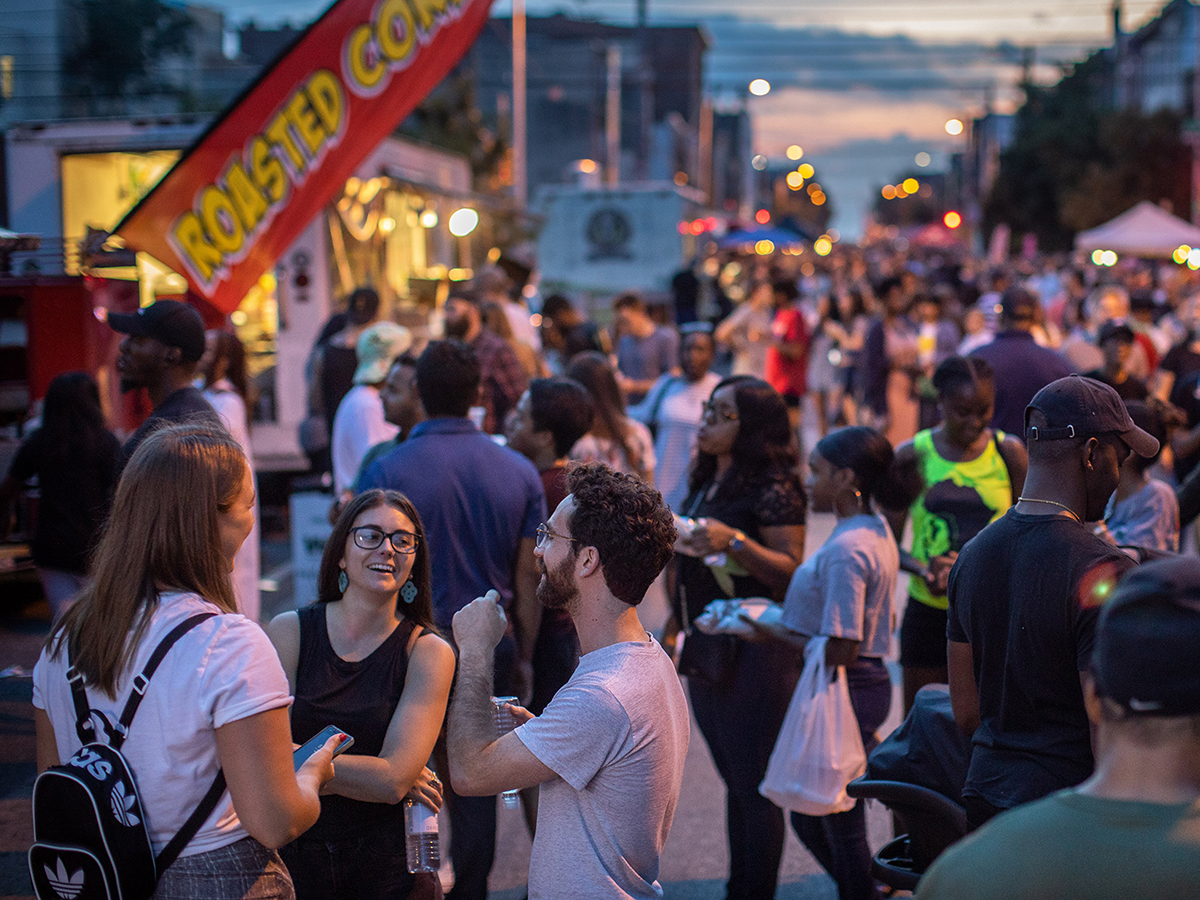 People walk through a street lined with food trucks and vendors at the Northern Liberties Summer Night Market.